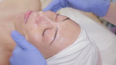 Profesyonel, bir kadın müşterinin yüzüne krem sürer. Kozmetoloji.