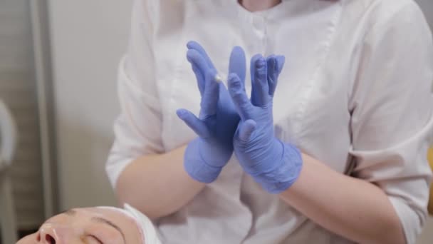 Profesional aplica crema a la cara de una mujer cliente. Cosmetología . — Vídeos de Stock