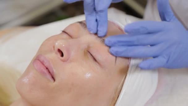 Professional applique de la crème sur le visage d'une cliente. Cosmétologie . — Video