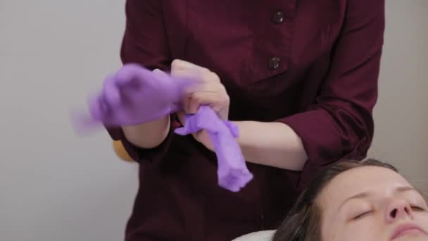 Professionelle Kosmetikerin zieht vor dem Eingriff Gummihandschuhe an. — Stockvideo
