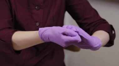 Profesyonel güzellik uzmanı mavi lastik eldivenleri antiseptikle tedavi ediyor.