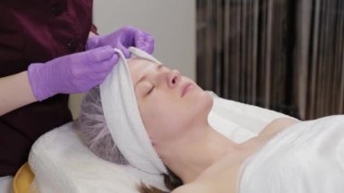 Profesyonel güzellik uzmanı kadın müşteriye şapka takıyor..