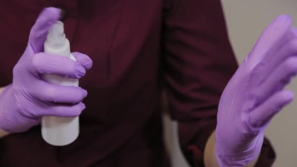 Professionele schoonheidsspecialiste behandelt blauwe rubberen handschoenen met een ontsmettingsmiddel — Stockvideo