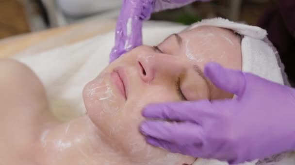 Professionell kosmetolog tvättar en kvinna och masserar hennes ansikte. — Stockvideo