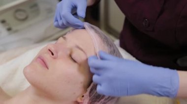 Profesyonel güzellik uzmanı kadın müşteriye şapka takıyor..