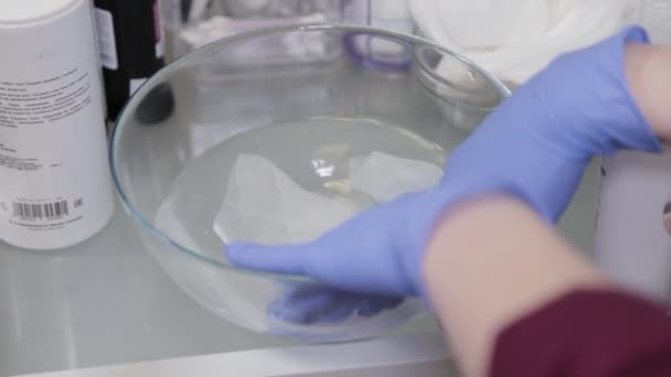 Een professionele schoonheidsspecialiste hydrateert doekjes in warm water om uw gezicht te wassen. — Stockvideo