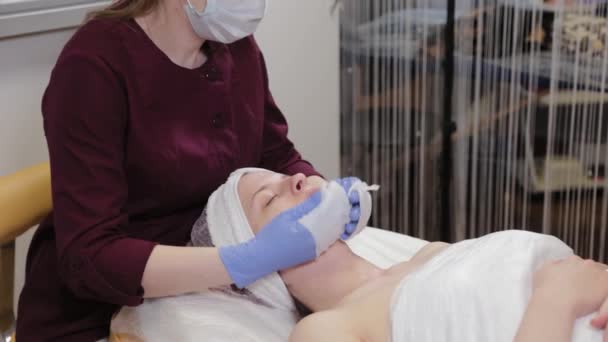 Professionele schoonheidsspecialiste wast het masker van het gezicht van een vrouw. — Stockvideo