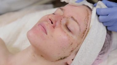 Profesyonel güzellik uzmanı bir kadının maskesini yıkar..