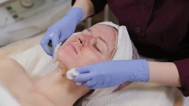 Professional beautician washes the mask off the face of a woman. — Stock Video