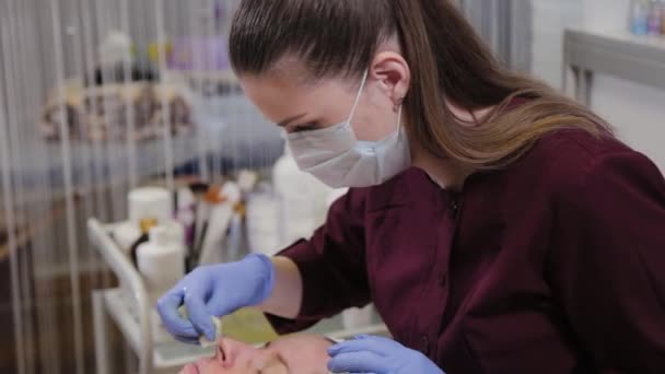 Estetista professionista lava la maschera dal viso di una donna. — Video Stock