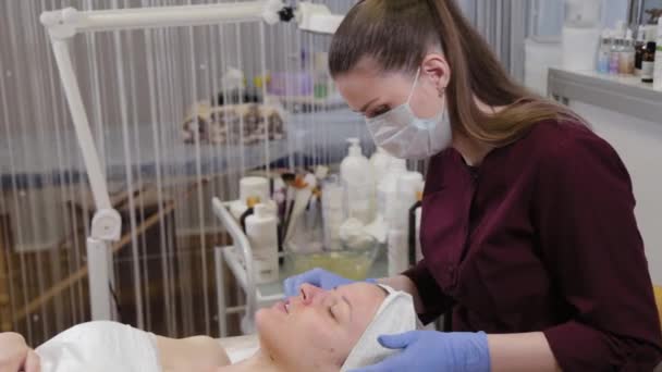 Professionelle Kosmetikerin wäscht einer Frau die Maske vom Gesicht. — Stockvideo