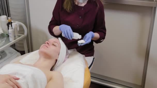 Професійний косметолог вимиває маску з обличчя жінки . — стокове відео