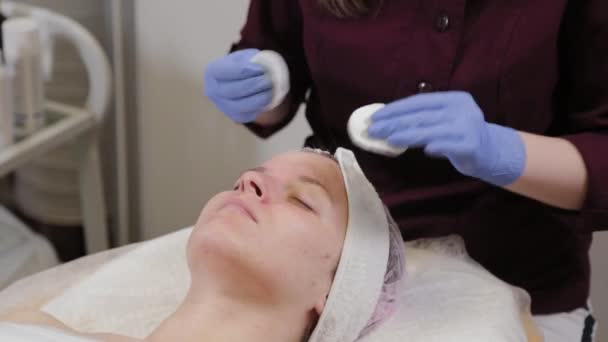 Esteticista profesional lava la máscara de la cara de una mujer . — Vídeos de Stock