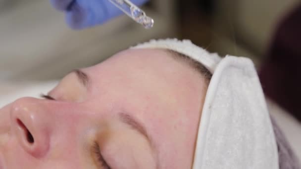 Esteticista profissional aplica o soro de uma pipeta ao rosto . — Vídeo de Stock