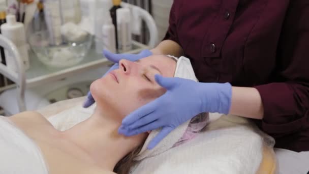 Een professionele schoonheidsspecialiste doet gezichtsmassage bij een vrouw. Cosmetologie. — Stockvideo