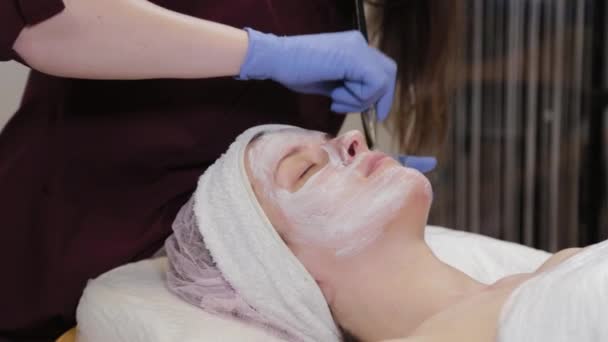 Professional beautician applying a face mask to a woman. — Stock Video