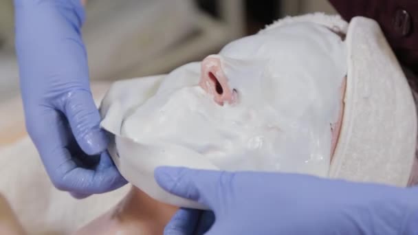 Professionele schoonheidsspecialiste verwijdert een gezichtsmasker van een vrouw. — Stockvideo