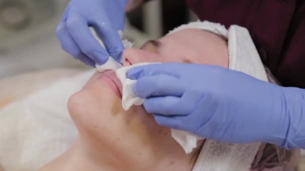 Esthéticienne professionnelle lave le masque sur le visage d'une femme. — Video