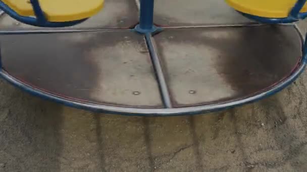 Roundabout merry go round spinning on empty playground with its shadow. — Stock Video