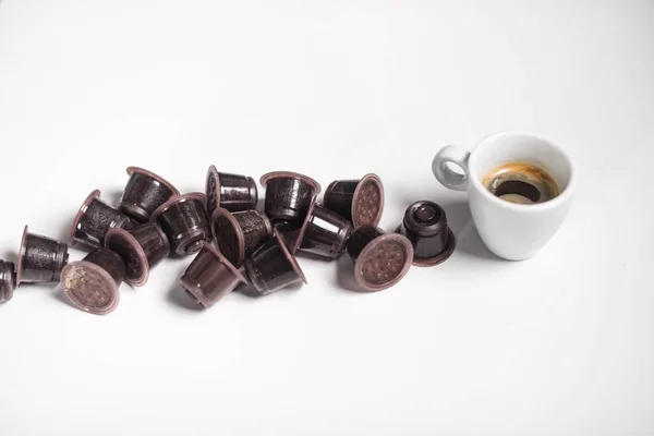 Used coffe capsules and espresso coffee over a white background. — Stock Photo, Image
