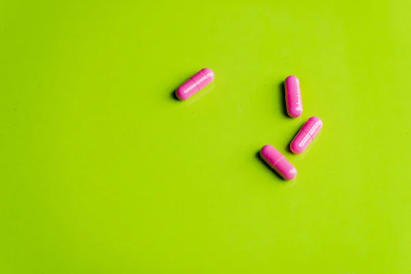 Pastillas de color rosa y la medicina sobre una mesa verde y backrgound . —  Fotos de Stock