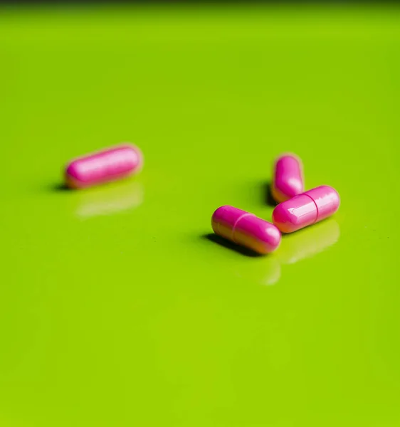 Pastillas de color rosa y la medicina sobre una mesa verde y backrgound . —  Fotos de Stock