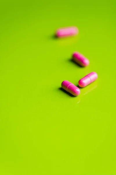 Rosa piller och medicin över ett grönt bord och backrgound. — Stockfoto