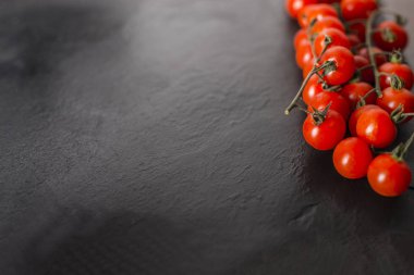 Kiraz domates kopya alanı ile siyah bir taş plaka üzerinde.