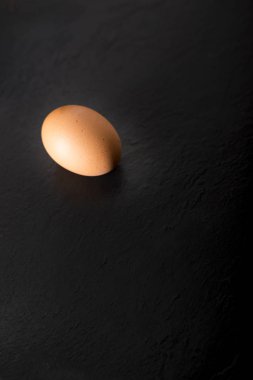 Kopya alanı ile siyah bir taş plaka üzerinde bir çiğ yumurta.