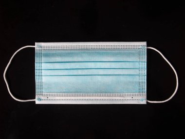 Ağzını ve burnunu lastik kulaklıklarla kapatmak için 3 katlı mavi cerrahi maske. Bakteri ve morfinden koruma maskesi. Tahta zemine uzan. Koruma kavramı.