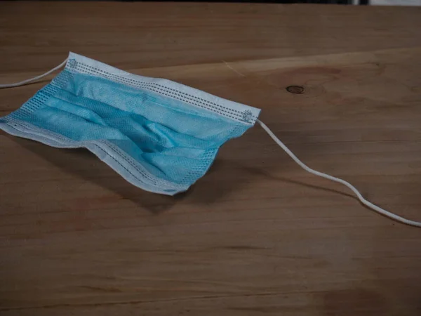 Ağzını ve burnunu lastik kulaklıklarla kapatmak için 3 katlı mavi cerrahi maske kullanılmış ve kırılmış. Bakteri ve morfinden koruma maskesi. Tek kullanımlık kavram.