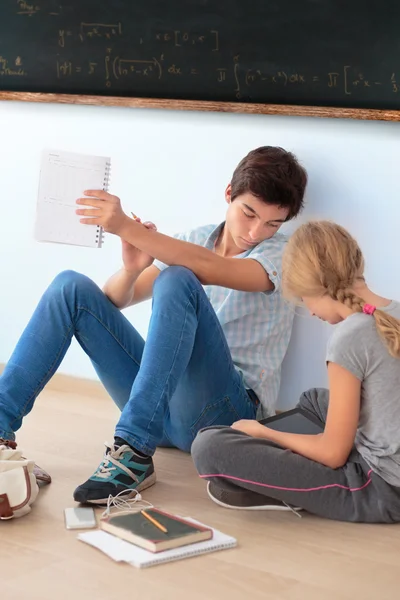 Teenagers learning by a blackboard in classroom — Stock Photo, Image
