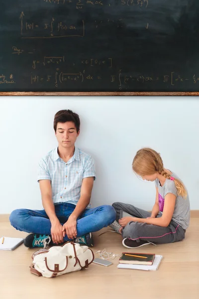 Tieners zitten door een schoolbord in de klas — Stockfoto
