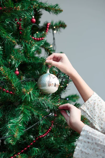 Young girl decorating Christmas tree with ball — Stock Photo, Image