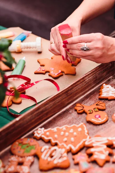 Frau dekoriert gebackene Weihnachtslebkuchen mit Frosti — Stockfoto