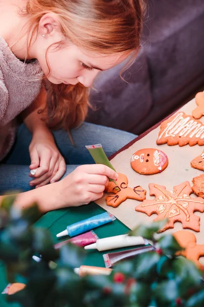 Mädchen dekorieren gebackene Weihnachtslebkuchen mit Frostin — Stockfoto