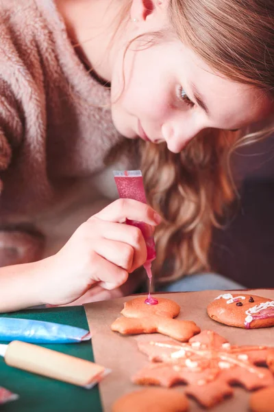 Girl decorating baked Christmas gingerbread cookies with frostin — Stock Photo, Image