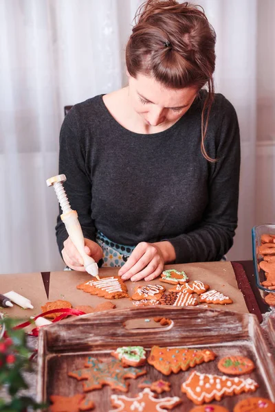 Frau dekoriert weihnachtliche Lebkuchen mit Zuckerguss — Stockfoto