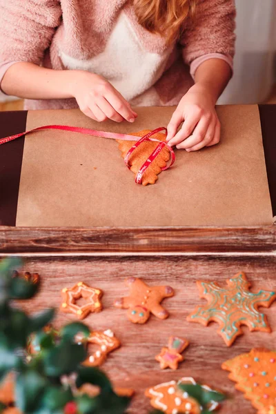 Mädchen bindet weihnachtliche Lebkuchen mit Schleife — Stockfoto