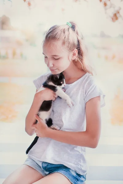 Mladá dívka v podřepu na verandě a objal svou kočku — Stock fotografie