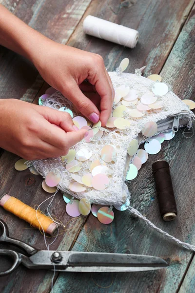 Girl decorating purse with sequins using thread needle and sciss — Stock Photo, Image