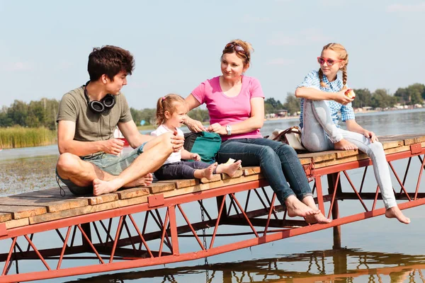 Family spending time together sitting on jetty over the lake in — Stock Photo, Image