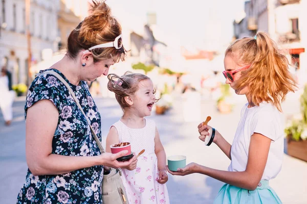 Pasar tiempo en familia juntos en el centro de la ciudad disfrutar de comer helado en un día de verano. Madre, niño y adolescente pasan tiempo de calidad en la tarde soleada comiendo postre dulce. Zona centro en el fondo — Foto de Stock