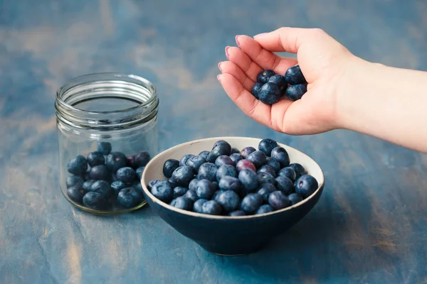 Woman putting freshly gathered blueberries from a jar into a sma — Stock Photo, Image