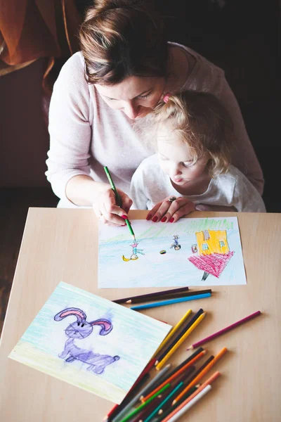 Mom with little daughter drawing a colorful pictures using penci