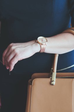 Pembe altın kol saati ve deri tutan mavi elbise giyen kadın