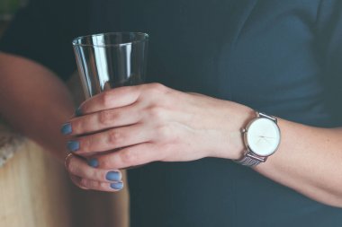 Gümüş Kol saati ve bardak tutan mavi elbise giyen kadın 