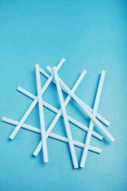 Mavi arkaplana saçılmış plastik pipetler