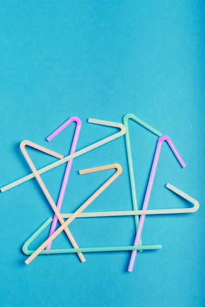 Heap of plastic drink straws scattered over blue background