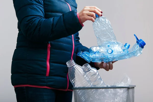 Woman collecting used plastic bottles and packagings in trash